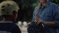 a woman holding a catchers mitt next to a young boy