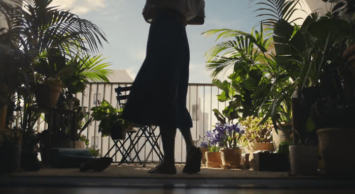 a woman holding an umbrella standing in front of potted plants