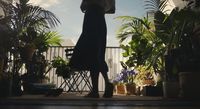 a woman holding an umbrella standing in front of potted plants
