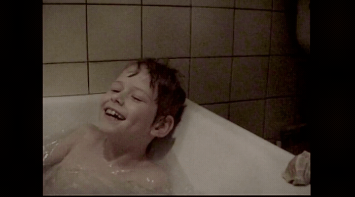 a young boy is laughing in a bathtub