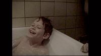 a young boy is laughing in a bathtub
