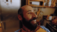 a man with a beard smiling in a kitchen