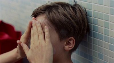 a young boy covering his face with his hands