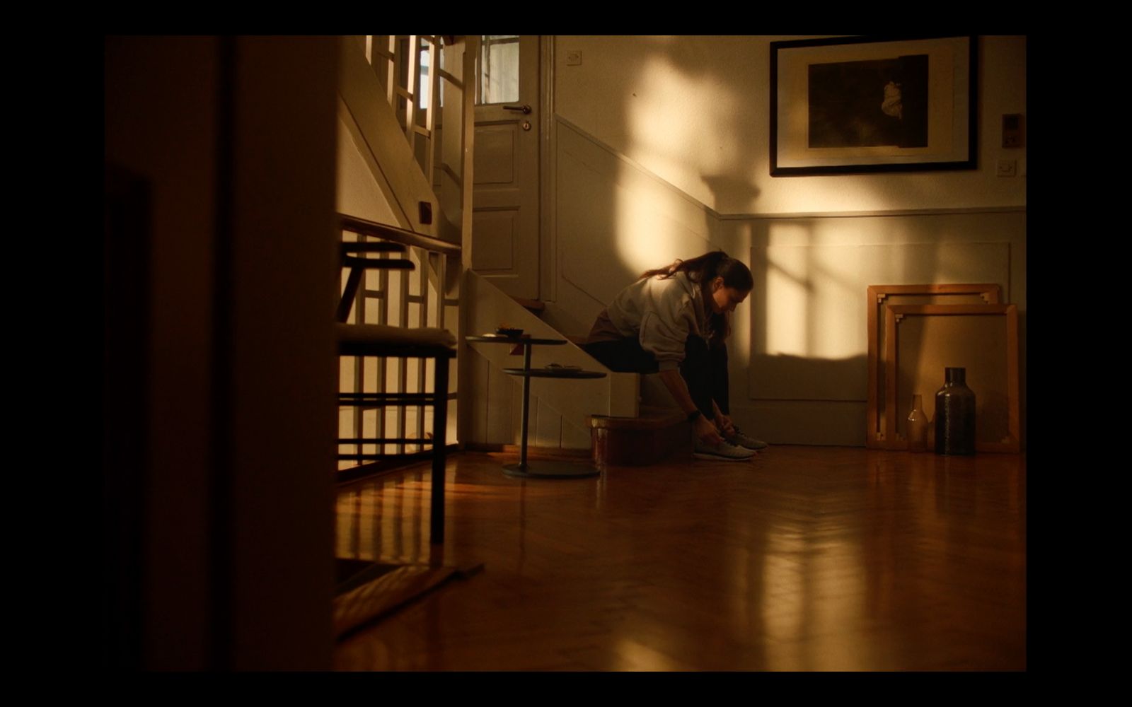 a woman standing on a hard wood floor next to a stair case