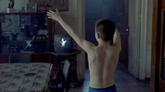 a shirtless man standing in a living room next to a table