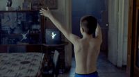 a shirtless man standing in a living room next to a table