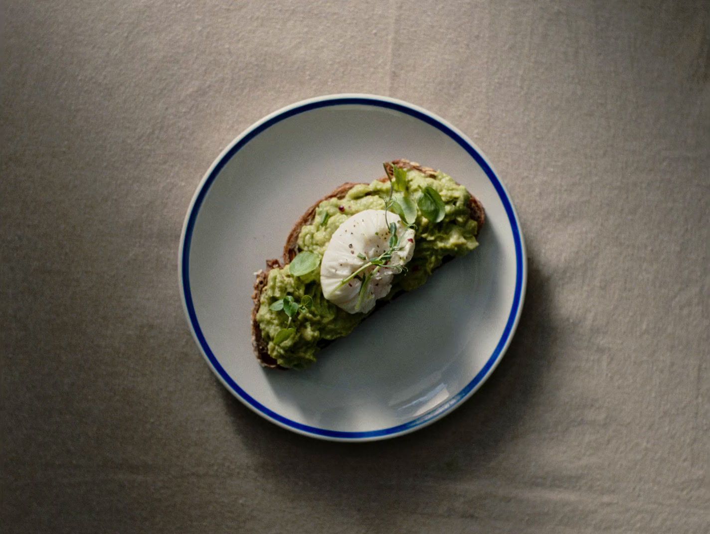 a white plate topped with a piece of bread covered in avocado