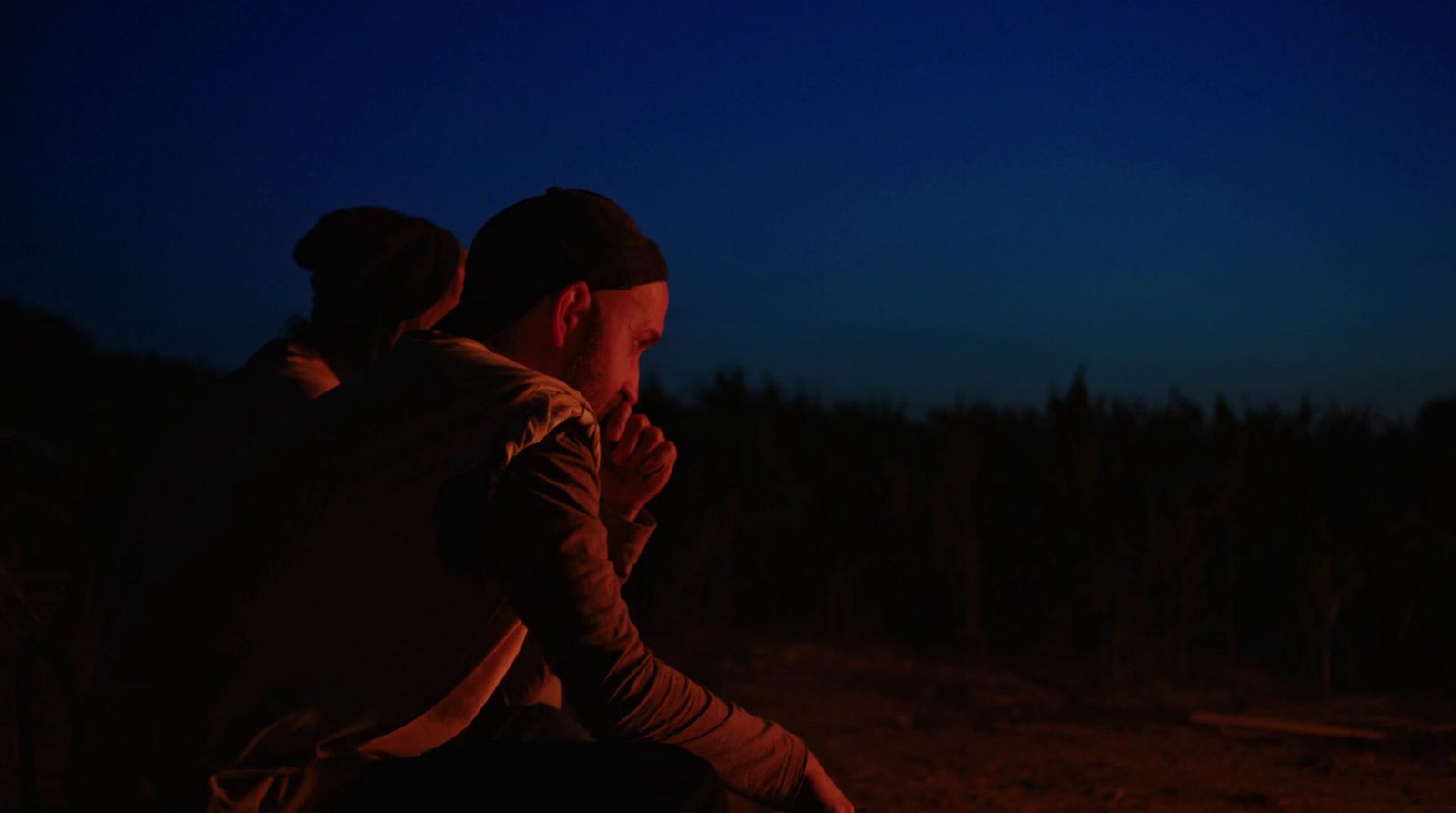 a man sitting in front of a campfire at night