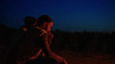 a man sitting in front of a campfire at night