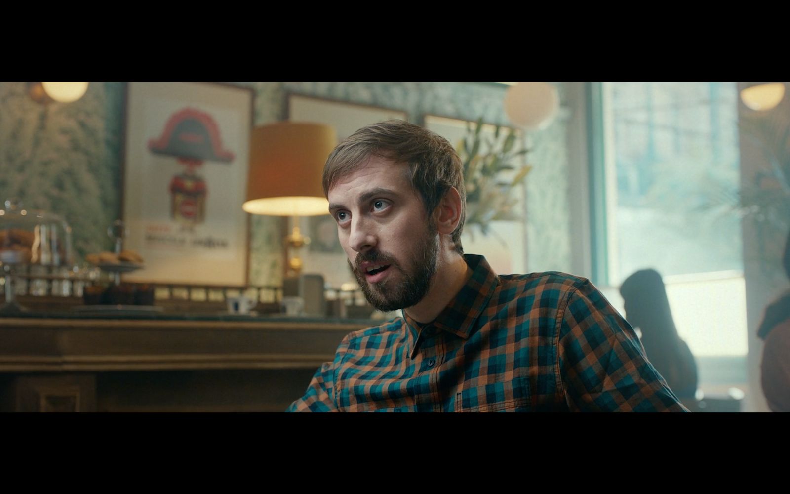 a man with a beard sitting in front of a window