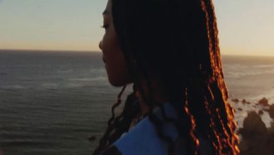 a woman looking out at the ocean at sunset