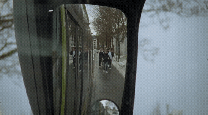 a rear view mirror on a vehicle reflecting people on the street
