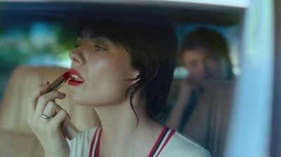 a woman sitting in a car smoking a cigarette