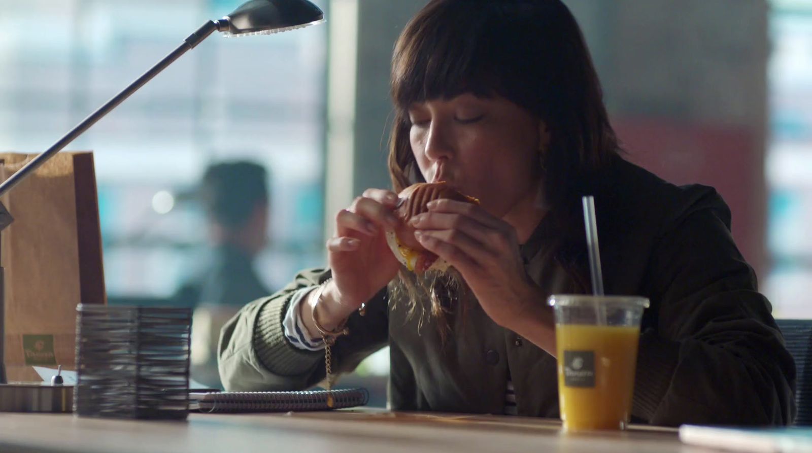 a woman sitting at a table eating a sandwich