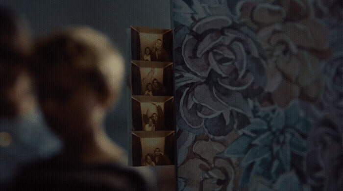 a woman standing in front of a wall with pictures on it
