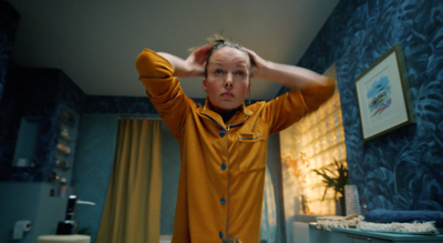 a woman in a yellow pajamas stands in a bathroom