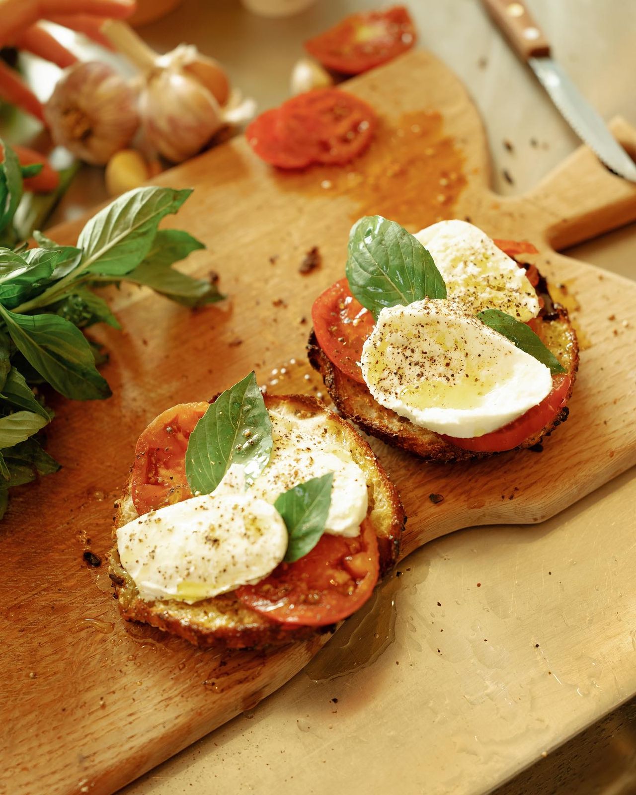 a wooden cutting board topped with two open faced sandwiches