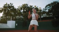 a woman in a white dress playing a game of tennis