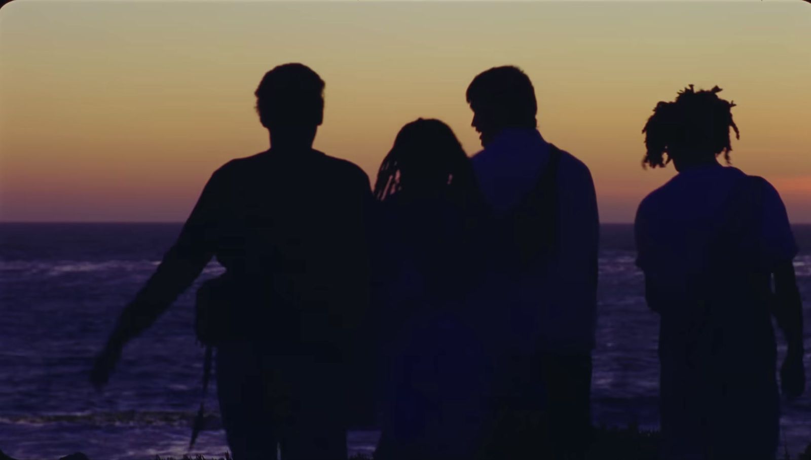 a group of people standing next to each other near the ocean