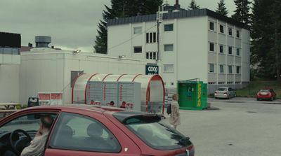 a red car parked in a parking lot next to a building