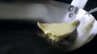 a piece of cheese is being cooked in a pan