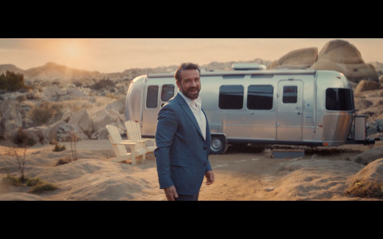 a man in a suit standing in front of a camper