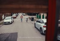 a couple of people walking down a street next to parked cars