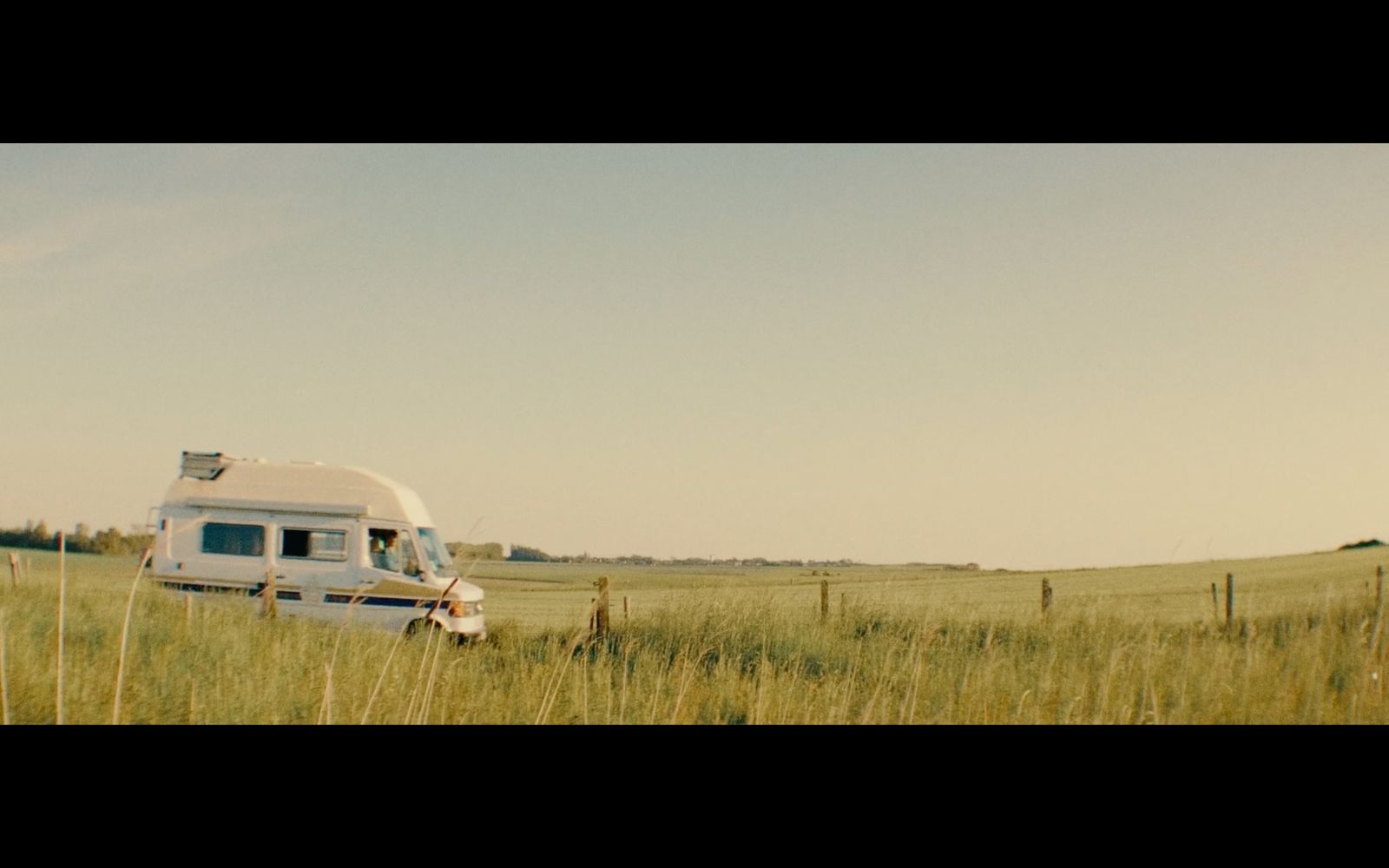 an rv is parked in a field of tall grass