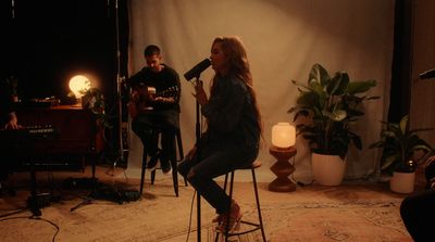 a woman sitting on a stool in front of a microphone