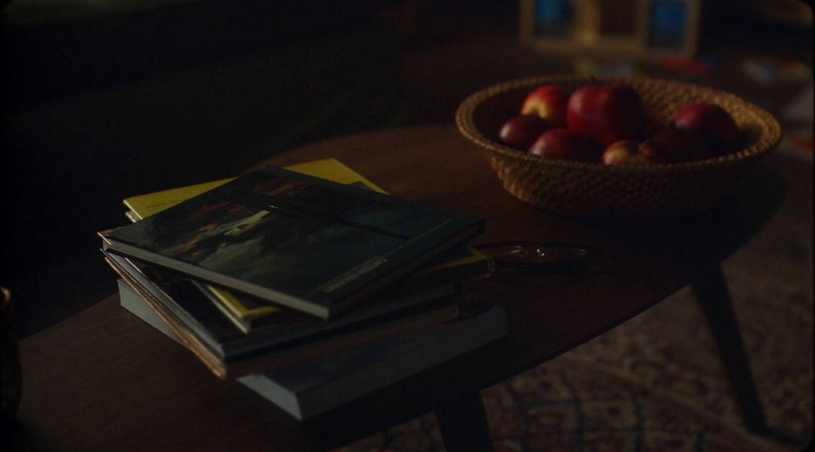 a wooden table topped with books and a bowl of apples