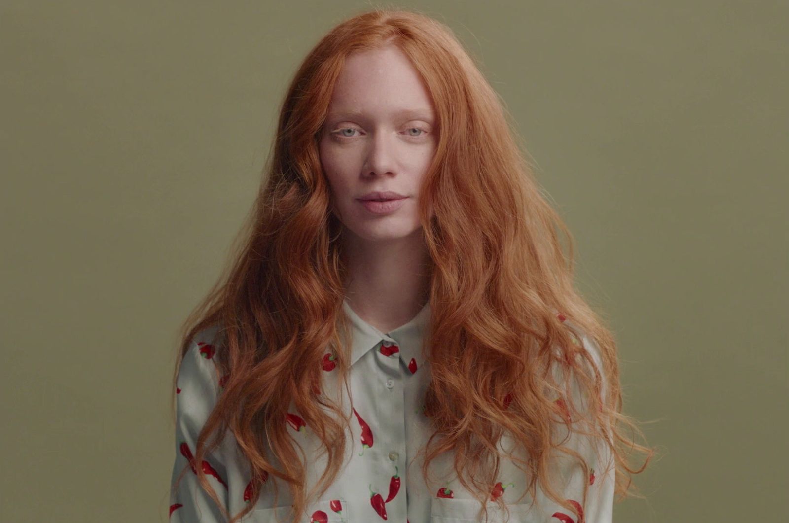 a woman with long red hair wearing a white shirt