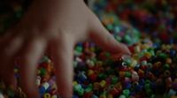 a hand reaching for a pile of colorful beads