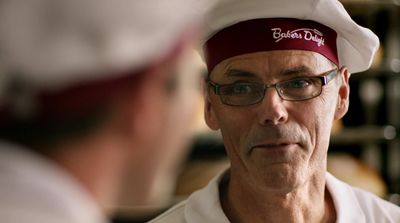 a man wearing a hat and glasses talking to another man