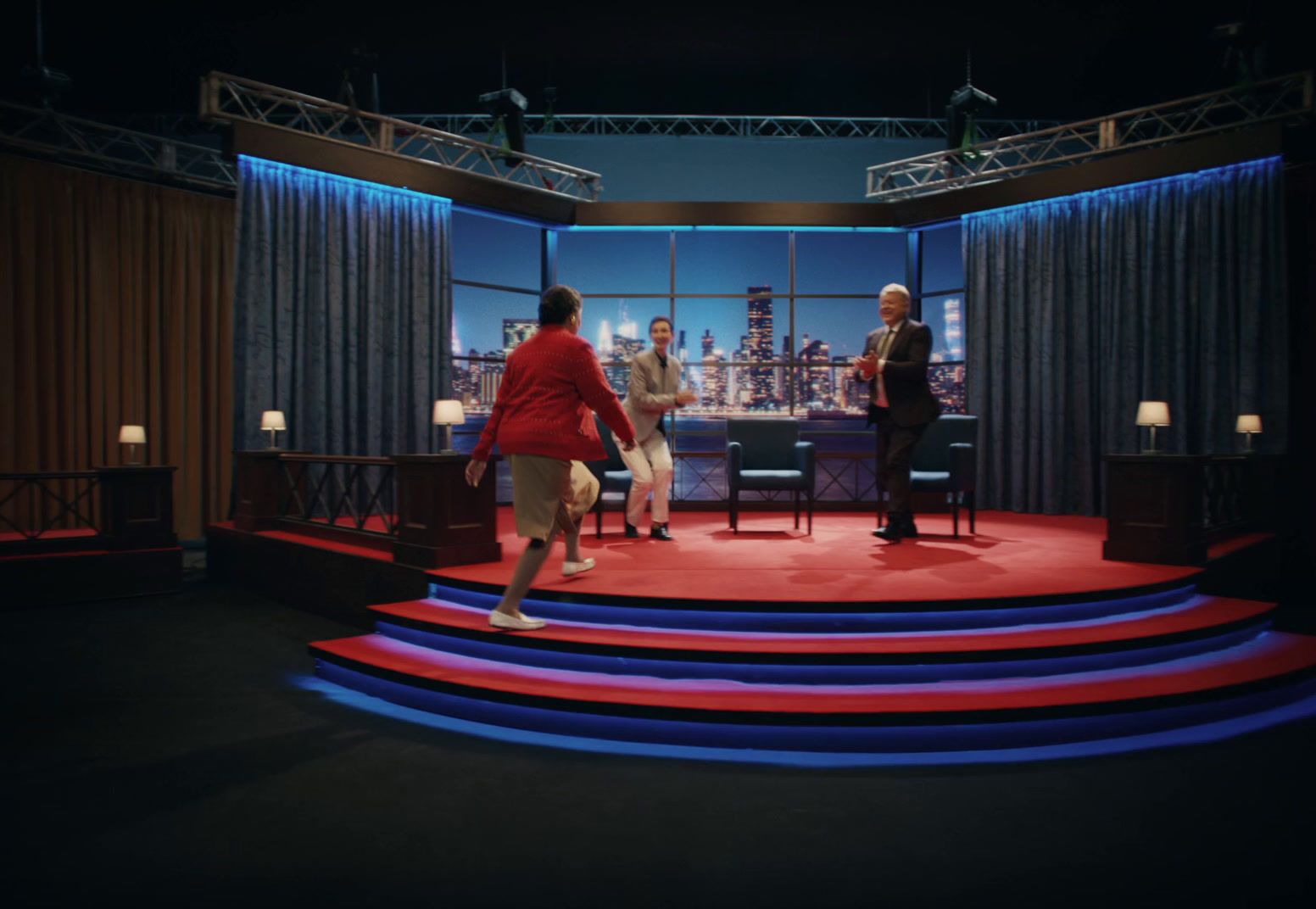 three people standing on a stage in front of a window