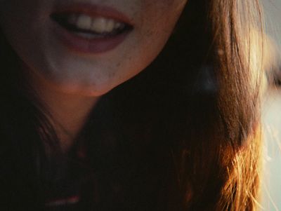 a close up of a woman's face with a cell phone in her hand