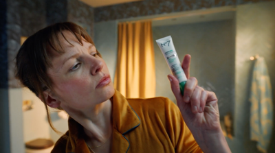 a woman holding a tube of toothpaste in her hand