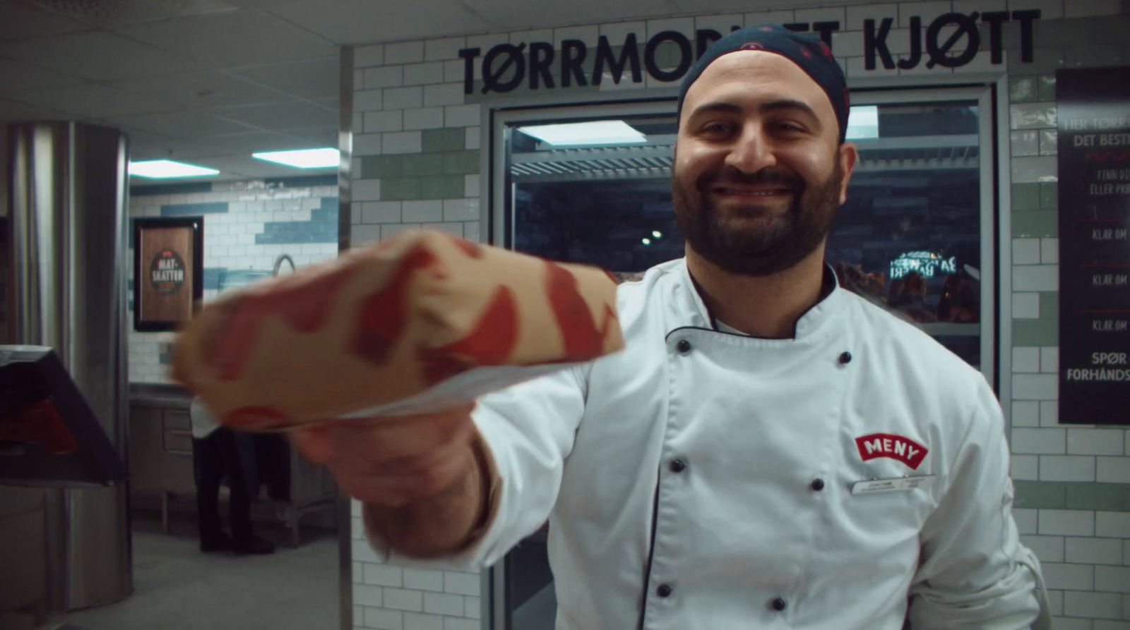 a man in a chef's coat holding a piece of food