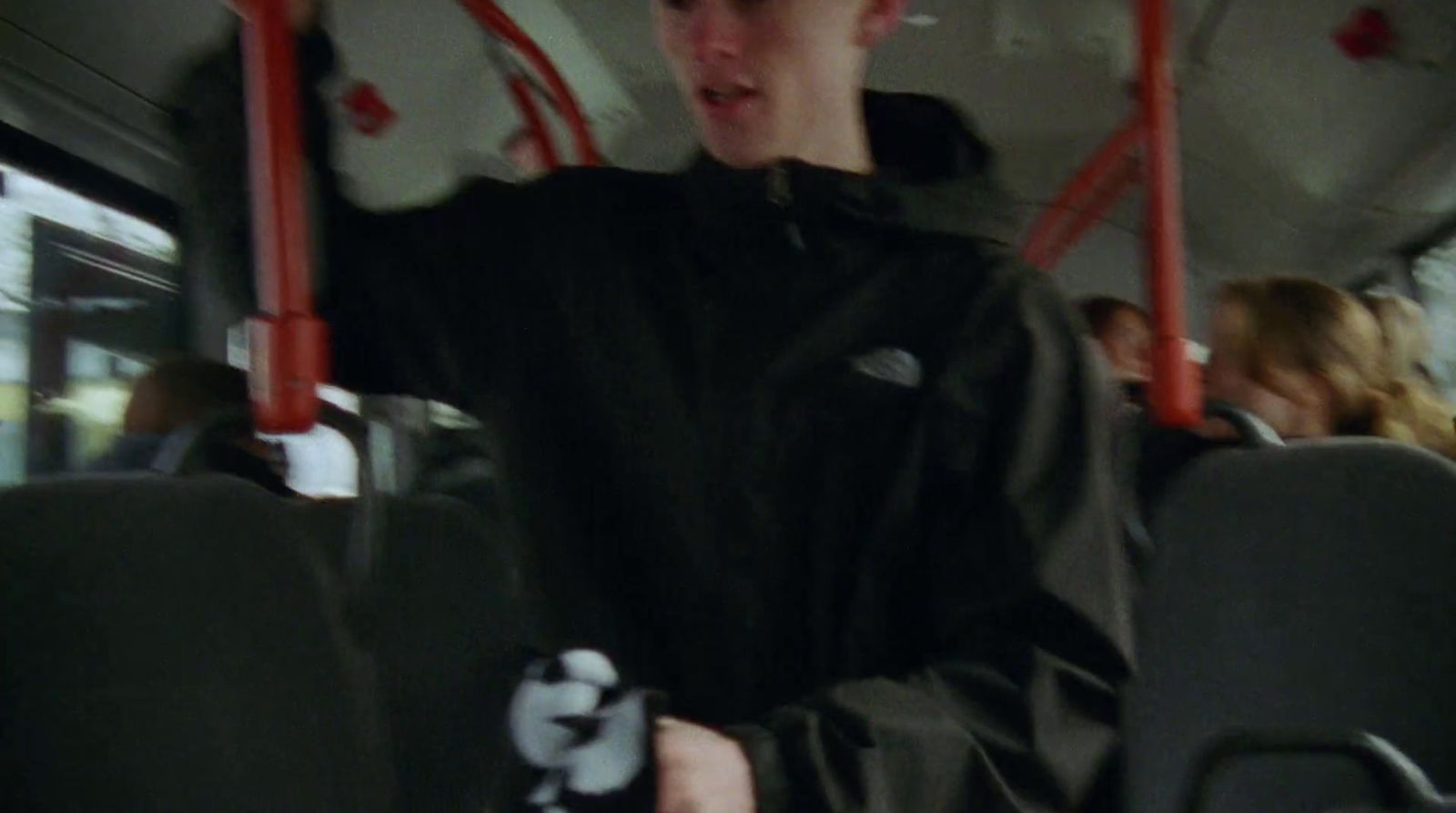 a man in a black jacket riding a bus