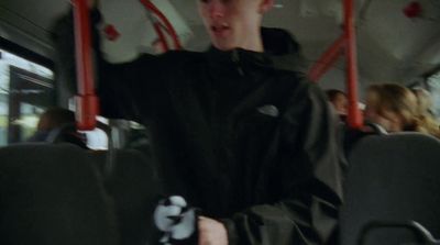 a man in a black jacket riding a bus