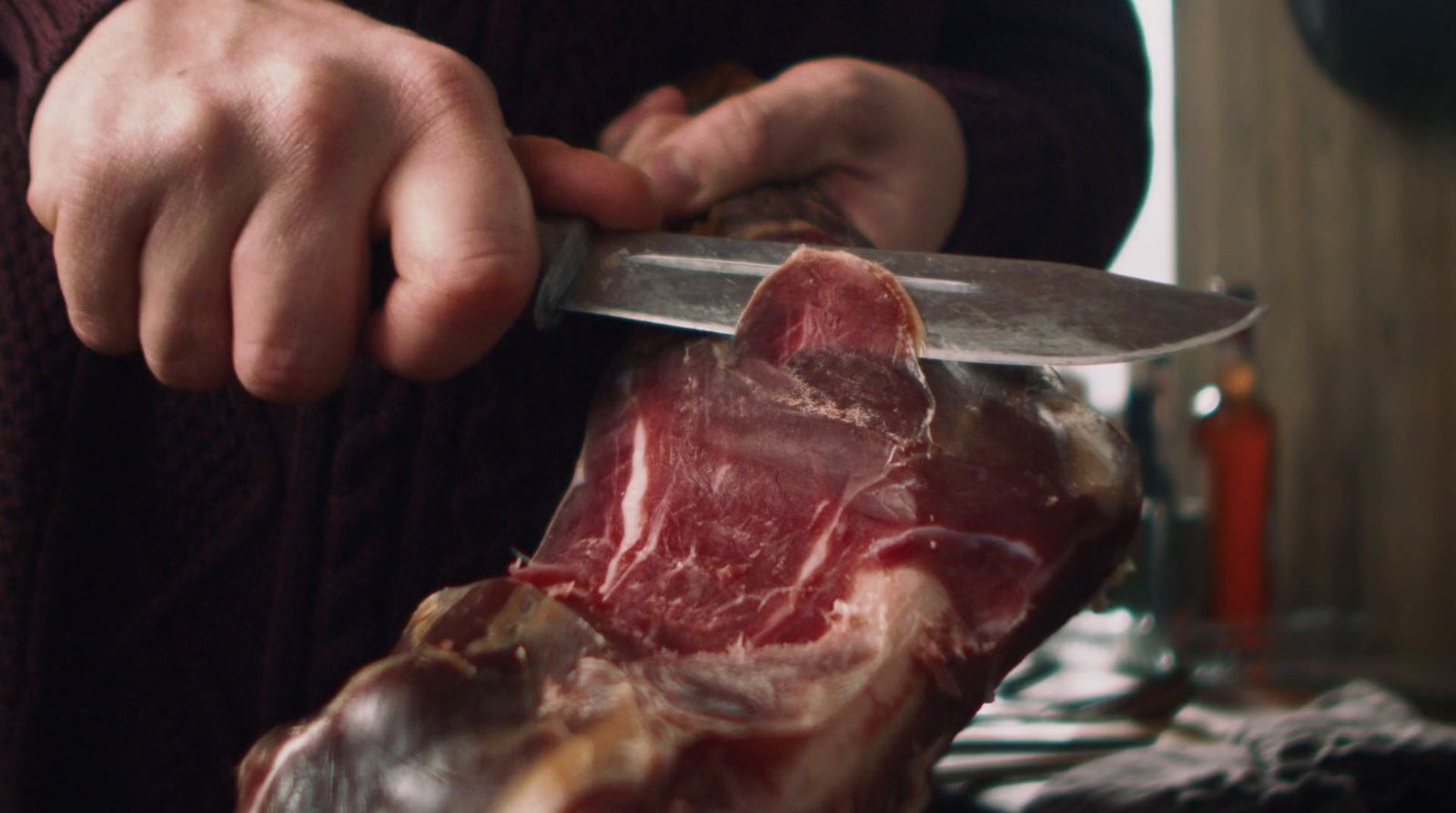 a person holding a knife cutting a piece of meat