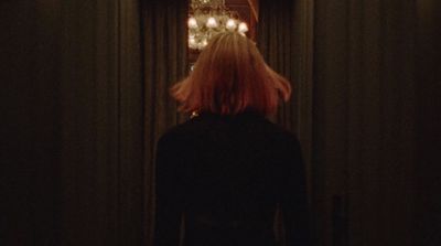 a woman standing in front of a chandelier in a dark room