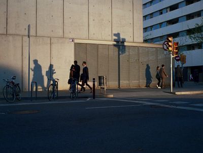 a group of people walking down a street next to a tall building