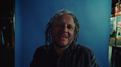 a man with dreadlocks standing in front of a blue wall