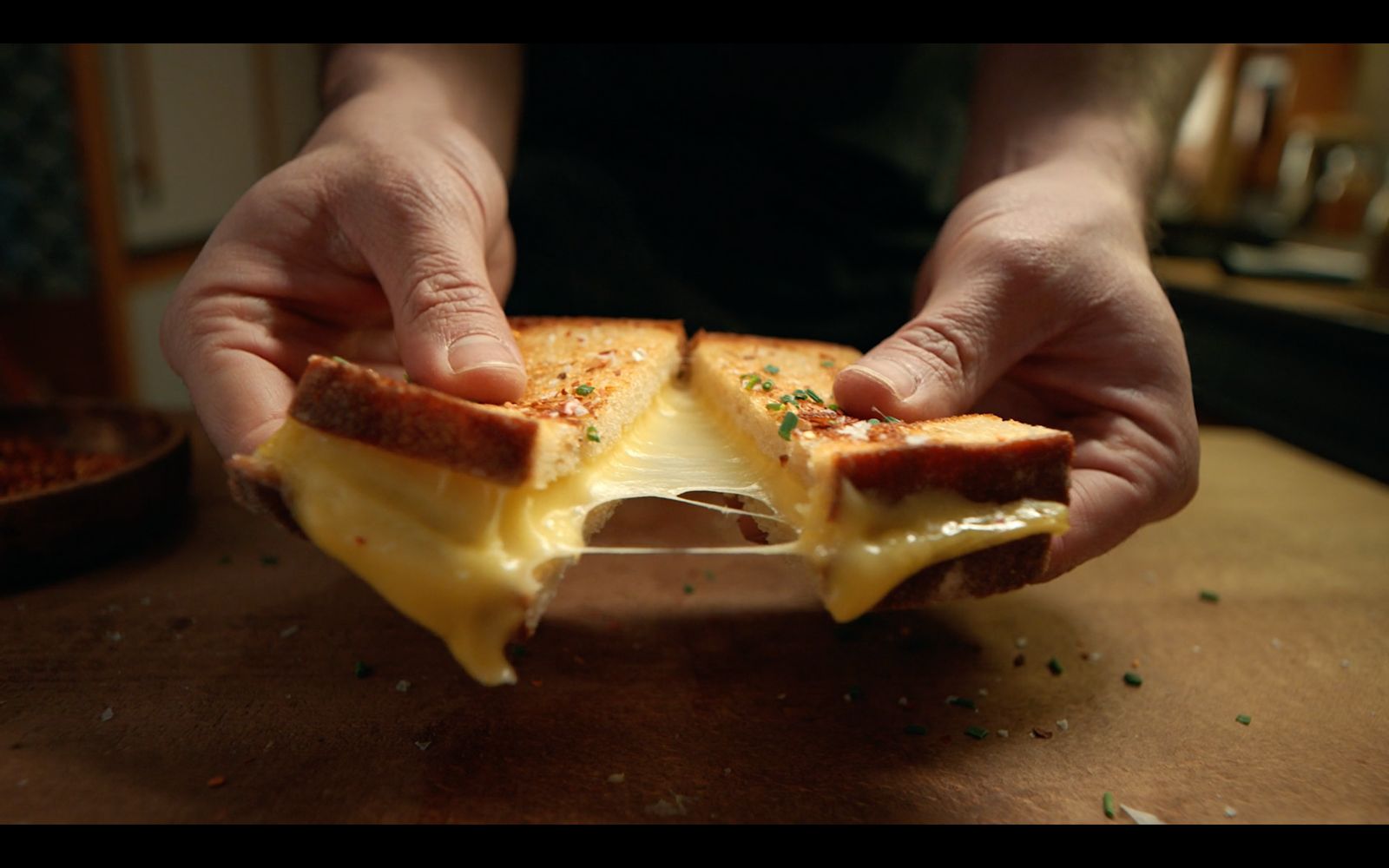 a person holding a piece of bread with cheese on it