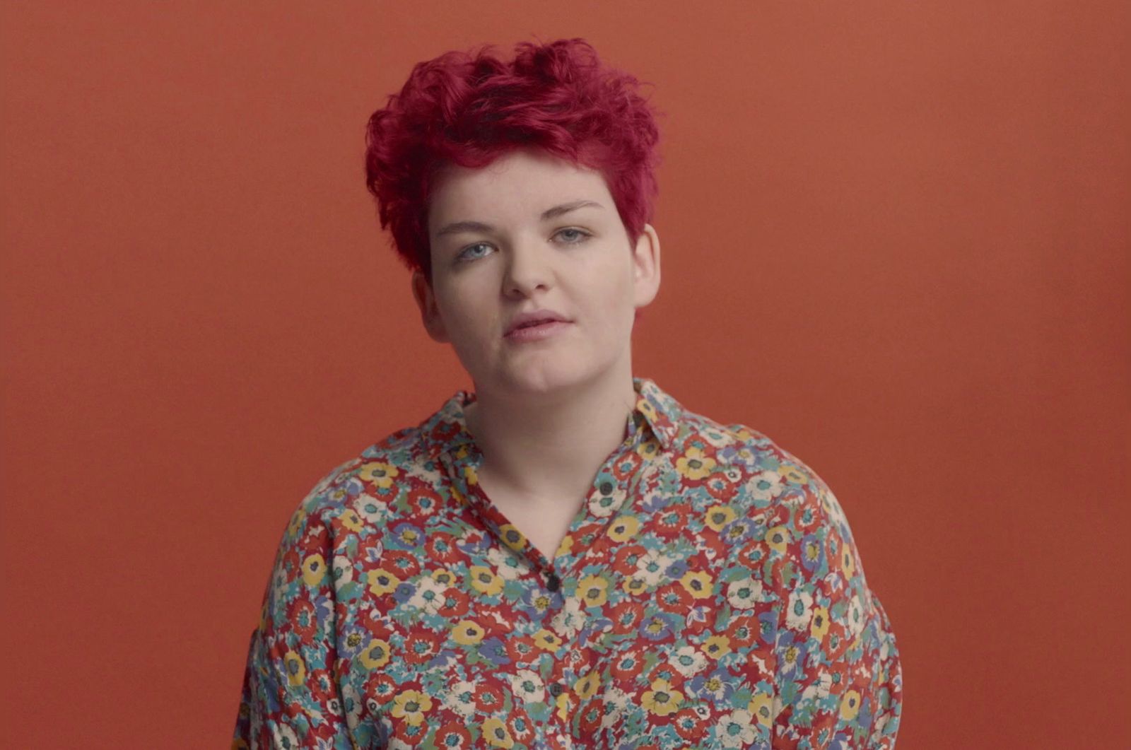 a woman with red hair wearing a floral shirt