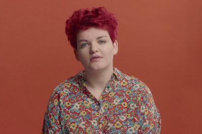 a woman with red hair wearing a floral shirt