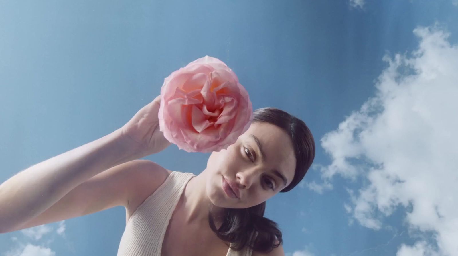 a woman holding a pink flower up to her face