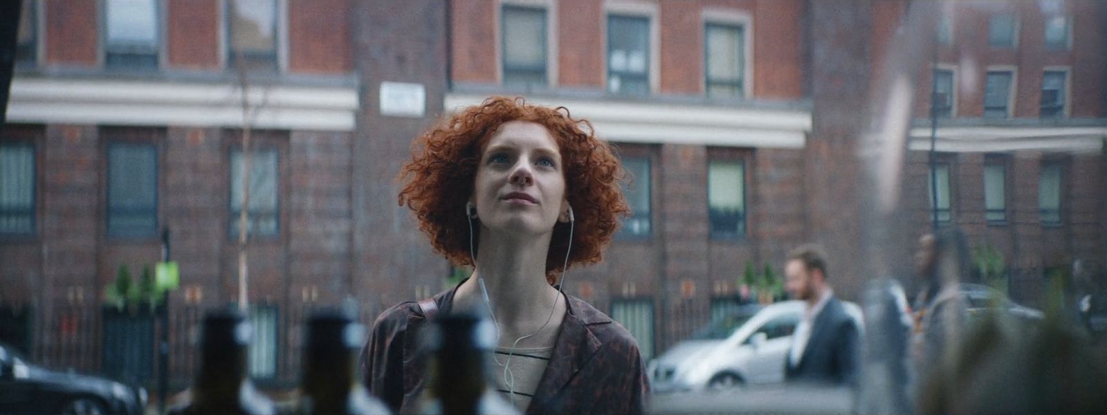 a woman with red hair standing in front of a building