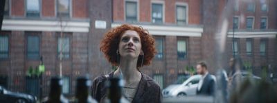 a woman with red hair standing in front of a building