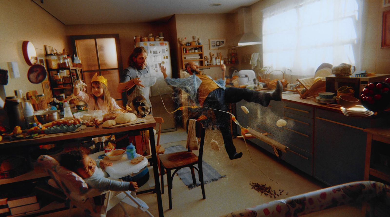 a group of people in a kitchen with a baby in a high chair